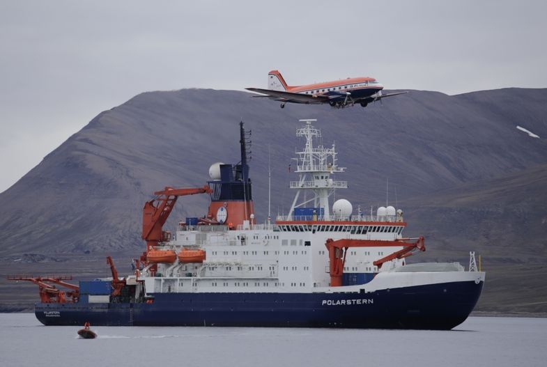 zur Vergrößerungsansicht des Bildes: Das Polarflugzeugeug Polar 5 fleigt über das Forschungsschiff in der Nähe von Longyearbyen (Svalbard). Foto: Alfred-Wegener-Institute / Thomas Krumpen (CC-BY 4.0)