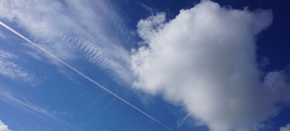 enlarge the image: Neben einer Cumuluswolke sind die hohen Eiswolken, die Zirren zu sehen. Darunter ist auch eine linienförmige Zirruswolke, ein Kondensstreifen von einem Flugzeug. 