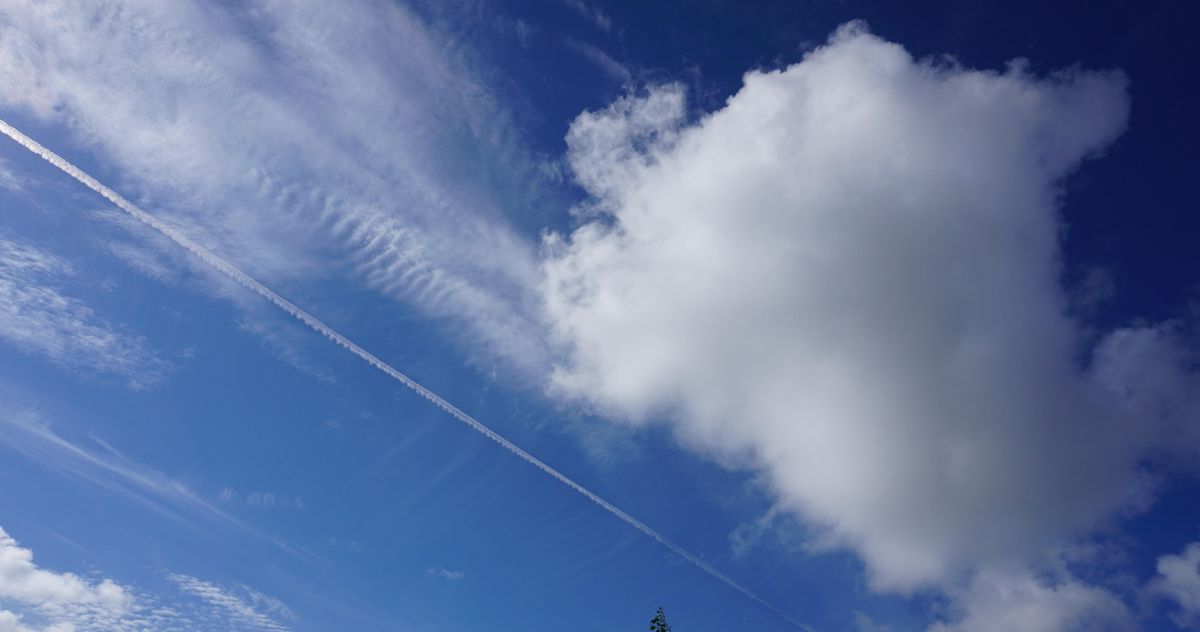 enlarge the image: Neben einer Cumuluswolke sind die hohen Eiswolken, die Zirren zu sehen. Darunter ist auch eine linienförmige Zirruswolke, ein Kondensstreifen von einem Flugzeug. 