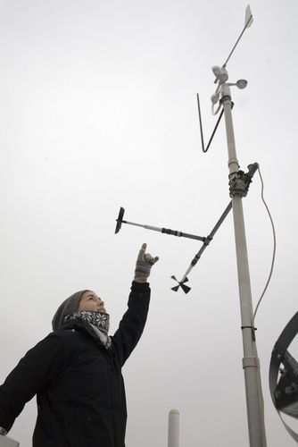 Studentin steht draußen und zeigt auf ein großes metereologisches Messgerät, Foto: Christian Hüller