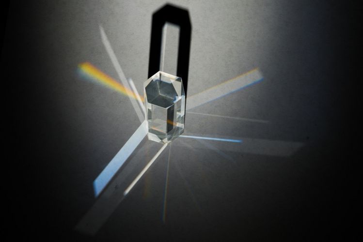 Beleuchtetes Prisma - unterschiedliche austretende Lichtsäulen entsprechen teils komplizierten Strahlenpfaden des einfallenden Lichtes durch das Prisma.