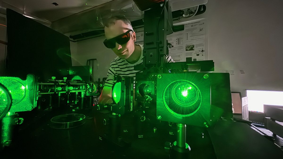 enlarge the image: Researcher working on an optical setup using green laser light