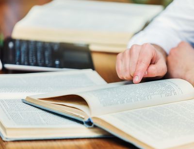 Zwei Bücher liegen aufgeschlagen auf dem Tisch vor einem Laptop. Foto: Colourbox