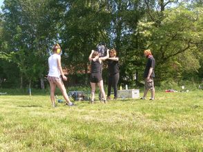 Studierende und Mitarbeiterinnen des Instituts für Geographie führen während eines Feldpraktikums eine Rammkernsondierung auf einer Wiese bei Sonnenschein durch, Foto: C. Zielhofer