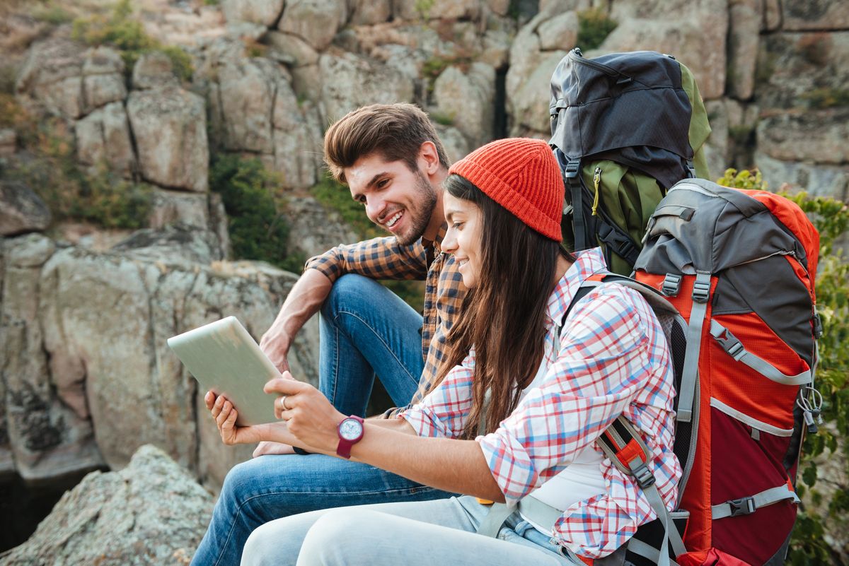 enlarge the image: A man and a woman sit in the mountains looking at a tablet. Photo: Colourbox