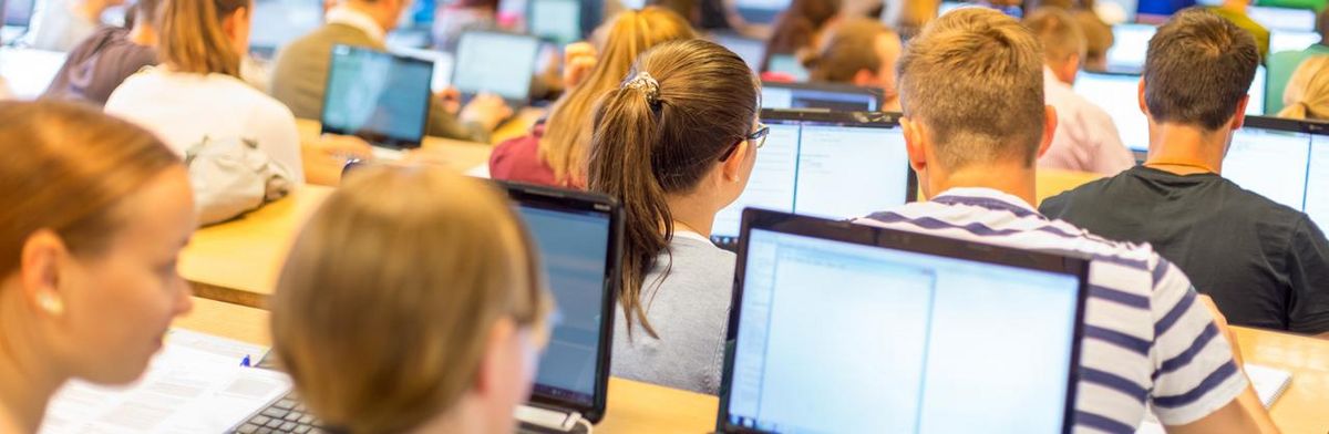 zur Vergrößerungsansicht des Bildes: Studierende im Hörsaal mit Laptops bei einer Vorlesung