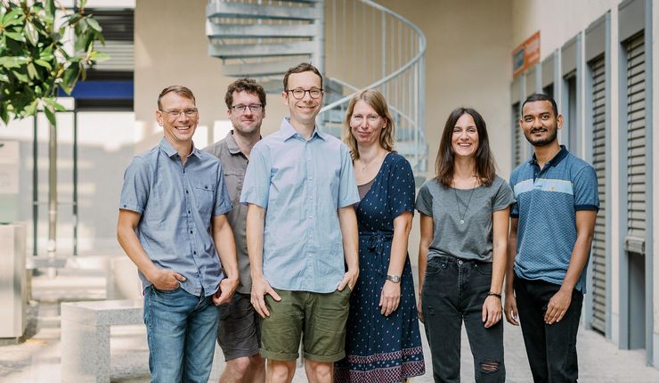 Two women and 4 men stand in front of a spiral staircase in an inner courtyard. Photo: Stephan Flad