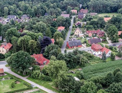 Eine Luftansicht von Zeitz zeigt rote Häuserdächer zwischen grünen Bäumen und Wiesenflecken.