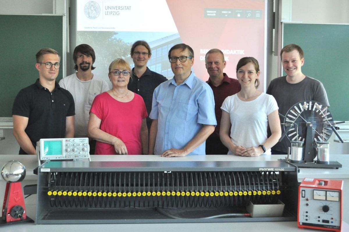 zur Vergrößerungsansicht des Bildes: Gruppenfoto der Abteilungen Fachdidaktik Physik und Hochschuldidaktik Physik mit Experimentiergerätschaften im Vordergrund, Foto: Grit Müller, Universität Leipzig