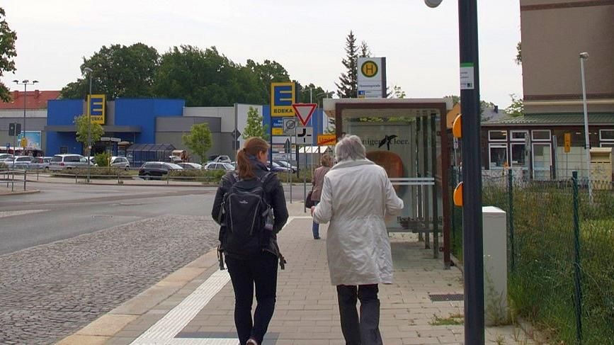 zur Vergrößerungsansicht des Bildes: Eine junge und eine ältere Frau gehen nebeneinander auf dem Fußweg und unterhalten sich.