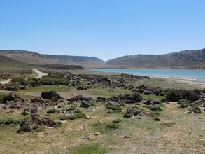 Foto vom See Sidi Ali im Mittlerer Atlas (Marokko) mit Basaltsteinen am Ufer bei Sonnenschein, Foto: A. Köhler