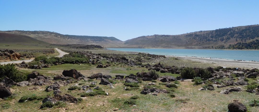 Foto vom See Sidi Ali im Mittlerer Atlas (Marokko) mit Basaltsteinen am Ufer bei Sonnenschein, Foto: A. Köhler