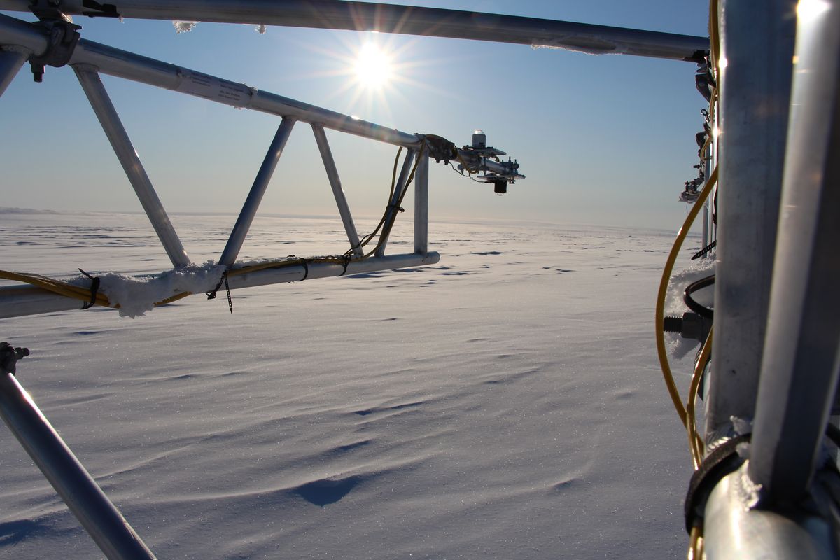 zur Vergrößerungsansicht des Bildes: Ein Messsystem mit Strahlungssensoren steht in der schneebedeckten, ebenen Landschaft in Nordgrönland. Foto: Tobias Donth